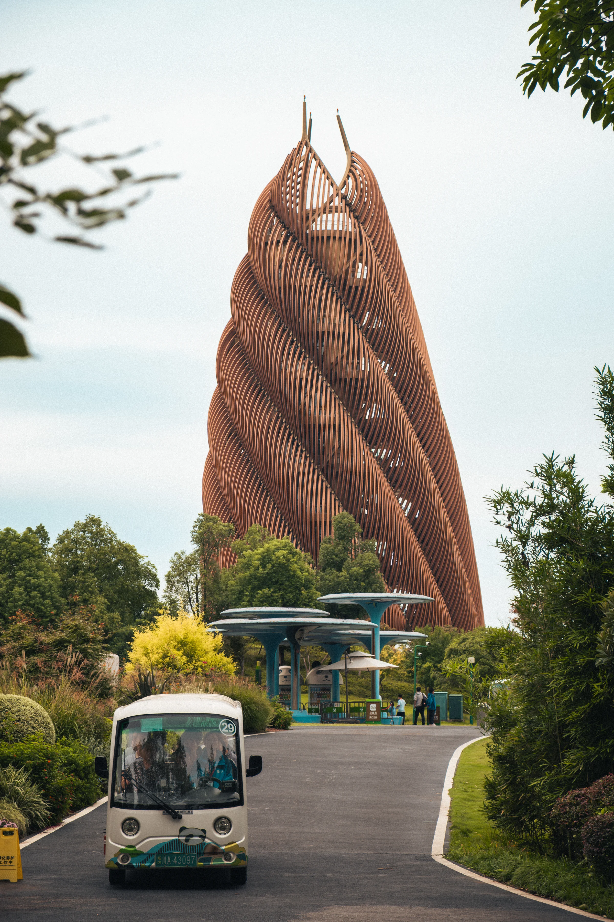 Contemporary observation tower shaped like a giant woven structure, electric cart customized panda style below, panda research base in Chengdu.